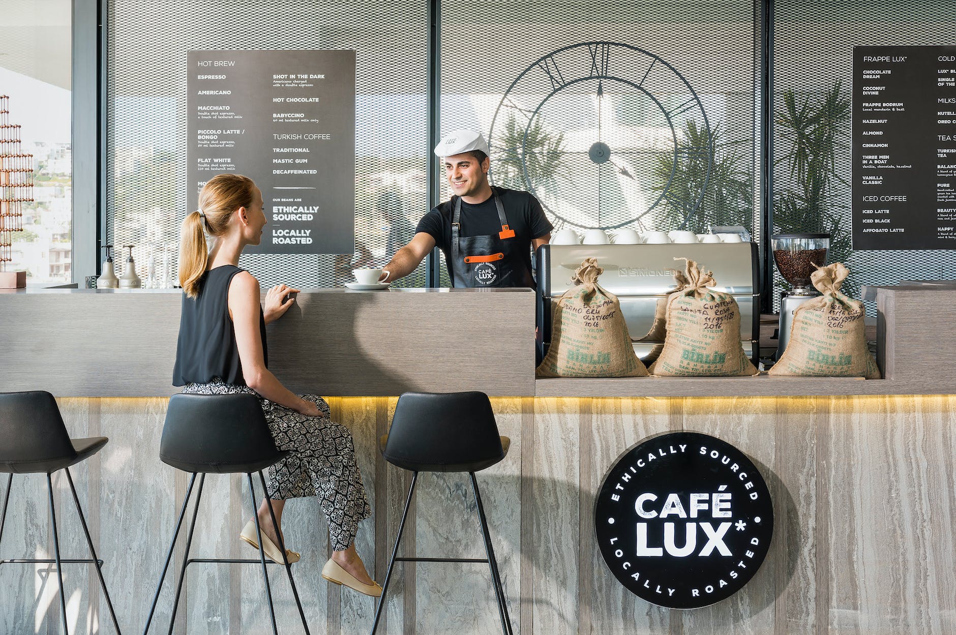 woman sitting on bar chair near barista